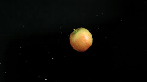 Wet Apple in Midair Captured in Slow Motion on Dark Background