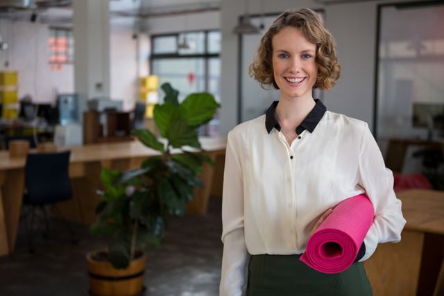 Portrait of female graphic designer holding yoga mat