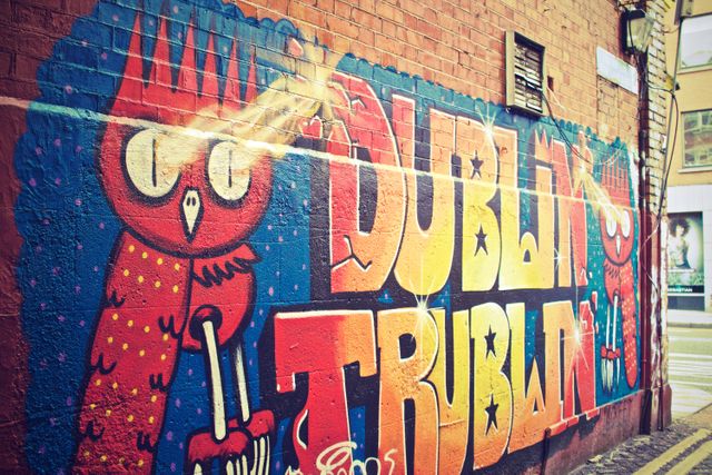 This image captures a vibrant and colorful piece of street art in Dublin, featuring a stylized red owl and bold, brightly colored letters. Ideal for use in travel blogs, articles about urban culture, street art collections, and promotional materials for Dublin tourism highlighting the city's artistic side.