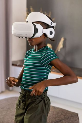 African teenage girl wearing vr headset exploring virtual world in modern living room