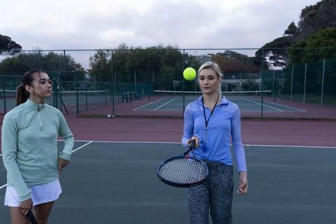 Female tennis coach training player on outdoor court during overcast practice