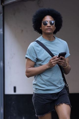 Urban commuter walking with smartphone, sunglasses and crossbody bag
