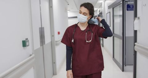 Female Doctor Removing Mask in Hospital Corridor