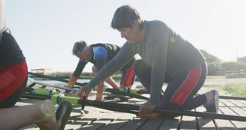 Senior Rowing Team Preparing Boat on Riverbank