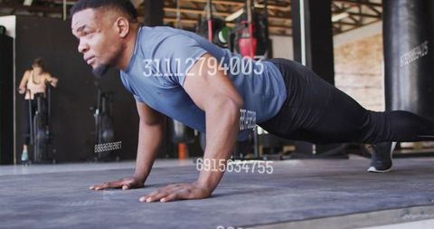 Muscular man holding plank on gym mat, performing intense core strength workout