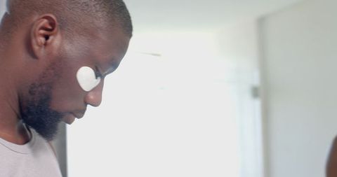 man applying under eye patch in natural light setting - Download Free Stock Images Pikwizard.com