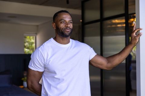 African american man standing in doorway, resting arm on frame, wearing white t-shirt