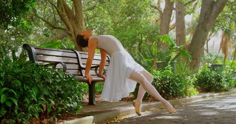 Graceful Ballerina Stretching in Sunlit Park Amid Green Trees - Download Free Stock Images Pikwizard.com