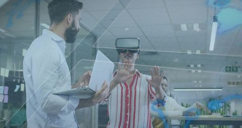 Team testing virtual reality interface in office while colleague presenting on laptop