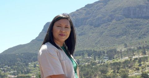 Asian woman standing on mountain overlook with valley view, rural road and forested ridge