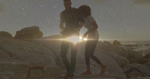 Romantic Couple Strolling Barefoot at Sunset on Rocky Beach