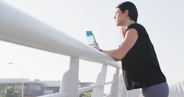 Woman Resting on Urban Bridge with Water Bottle During Morning Exercise - Download Free Stock Images Pikwizard.com