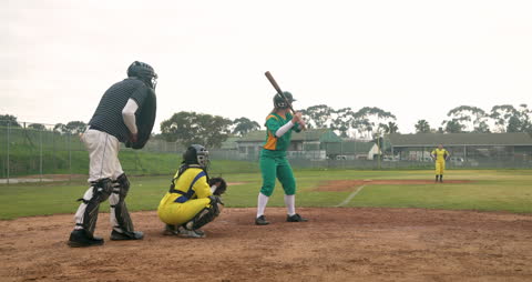 Female Baseball Player Batting During Match in Green Uniform