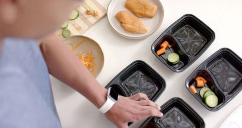African american man preparing healthy meal prep containers with chicken and fresh veggies