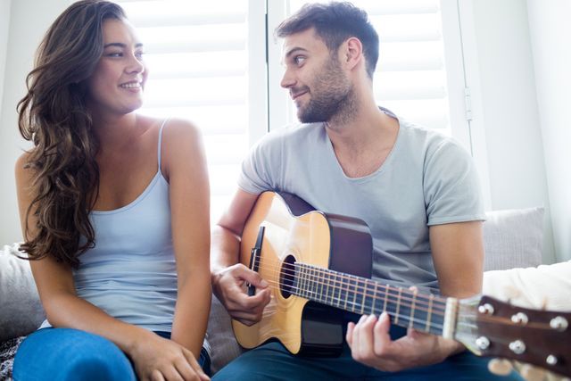 Man playing guitar for woman in bedroom - Download Free Stock Photos Pikwizard.com