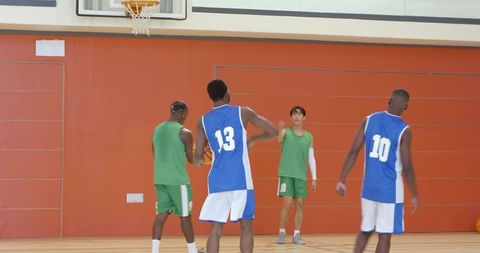 Multiracial male basketball players practicing free throws, rebounding and passing in indoor drill
