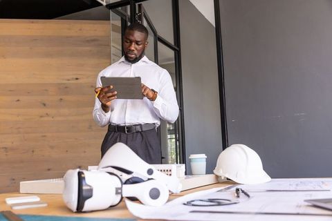 Architect Analyzing Plans on Tablet in Modern Office