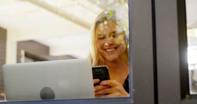 Young Woman Smiling While Using Smartphone and Laptop - Download Free Stock Images Pikwizard.com
