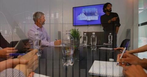 Presenter pointing at 3d house model on screen while team taking notes in boardroom