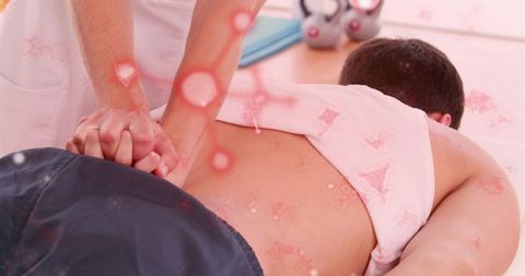 Male receiving therapeutic back massage on spa table with interlocked hands and pink towel