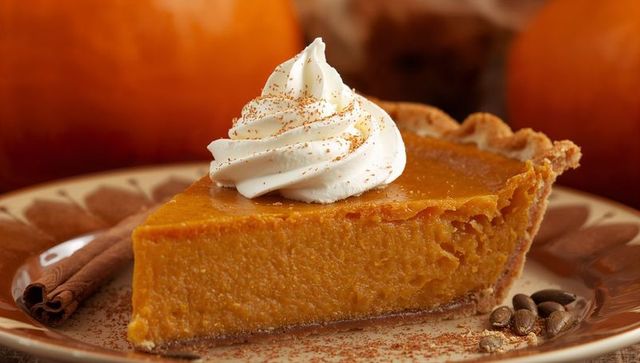 Serving creamy pumpkin pie slice topped with whipped cream and cinnamon for autumn dessert