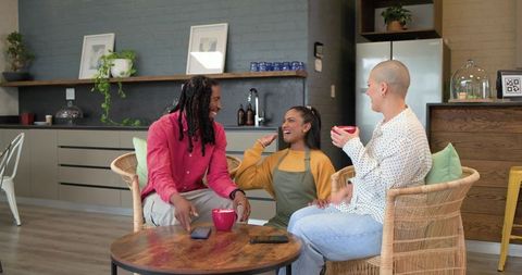 Multicultural friends chatting and laughing over coffee in modern cozy kitchen lounge
