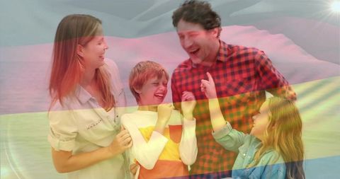 Laughing family enjoying beach day with rainbow flag overlay celebrating pride