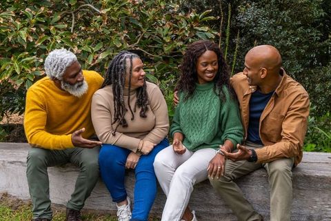 Multigenerational african american friends chatting and laughing on park bench