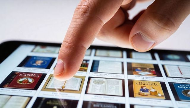Tapping fingertip selecting ebook thumbnail on tablet screen with bezel glare and reflections