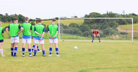 Soccer Teammates Forming Defensive Wall on Pitch Facing Ball