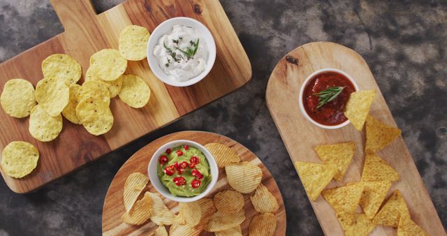 Close up view of variety of chips and sauces on wooden trays on black surface. food and snack concept