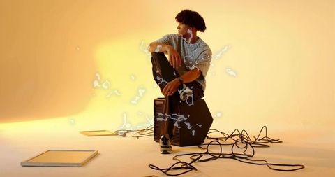 Modern Musician Relaxing in Studio Setting with Amplifier and Cables