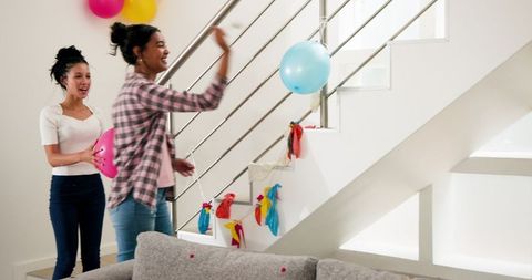 Two Women Decorating Staircase with Colorful Balloons for Celebration