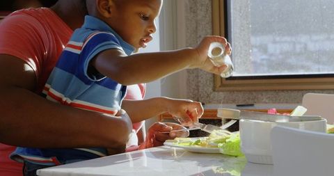Father and Son Preparing Meal in Sunlit Dining Room