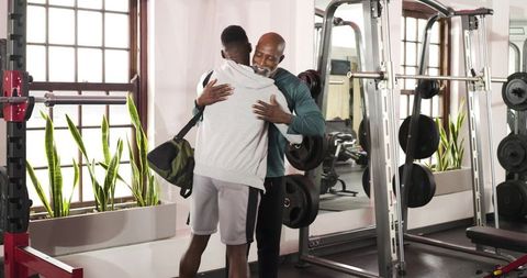 Gym trainer and client sharing hug after successful workout session