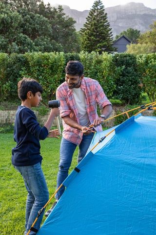 Father and son setting up blue tent for family outdoor adventure