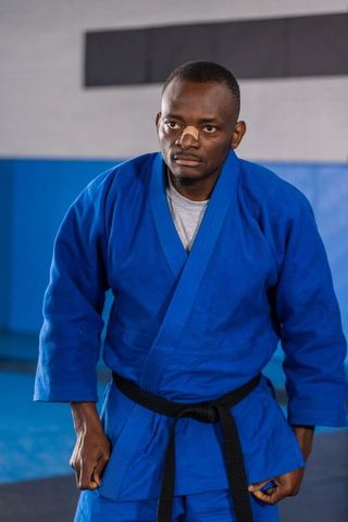 Focused martial artist in blue gi practicing in dojo