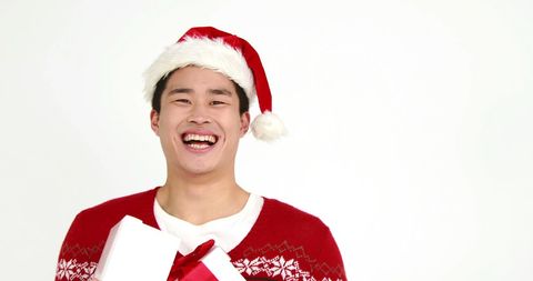 Joyful Young Man Holding Christmas Gift in Santa Hat