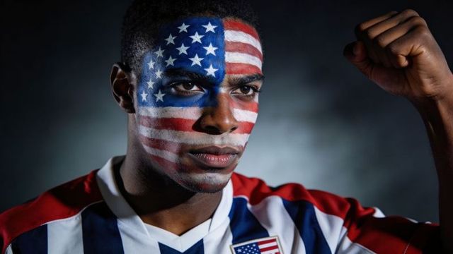 Determined american sports fan with stars and stripes face paint raising fist