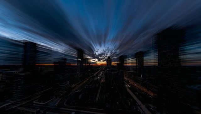 Framing pointed-roof tower silhouetting at sunset with radial motion streaks, light trails