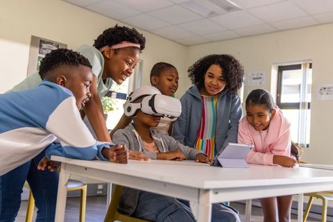 Diverse preteen students exploring virtual reality with vr headset and tablet in classroom