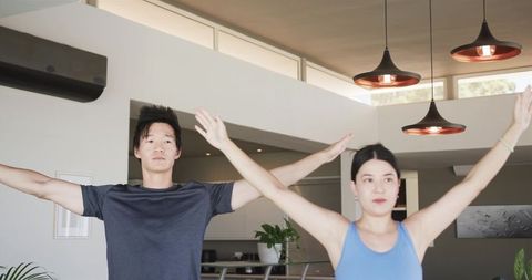 Young couple performing morning stretching routine in modern open-plan kitchen for home fitness