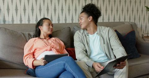 Young Couple Relaxing on Sofa Interacting with Tablets