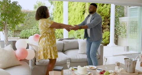 African american couple celebrating joyfully at home with dessert and drinks