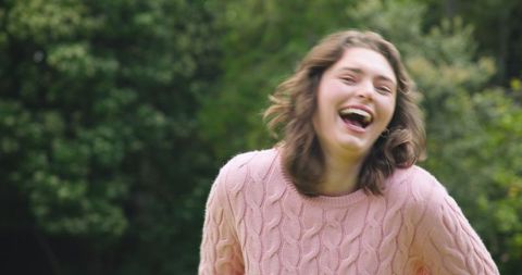 Joyful Woman Enjoying a Moment Outdoors in Stylish Pink Sweater