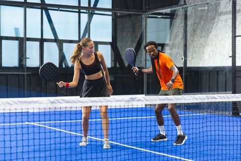 Energetic mixed doubles padel game action on blue court