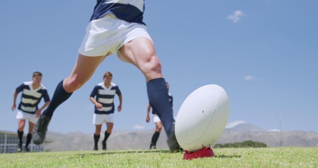 Low section of caucasian male rugby player kicking ball on tee on sunny sports field, copy space. Preparation, sport, team sport and competition, unaltered.