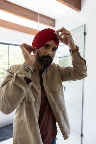 Indian man adjusting turban with natural light in stylish bathroom