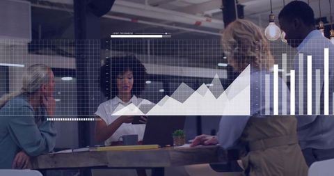 Diverse team collaborating over digital charts and devices in modern open-plan workspace