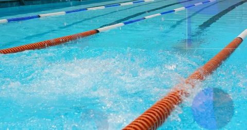 Splashing lane water in competition pool featuring orange and blue white lane dividers